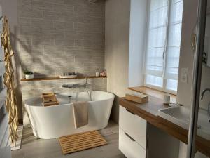 y baño con bañera blanca y lavamanos. en Gîte La Patouille, en Amboise
