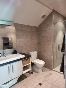 a bathroom with a toilet and a sink and a shower at The Sandy Golfer in Mount Maunganui