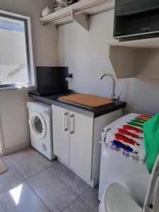 a small kitchen with a washing machine and a sink at The Sandy Golfer in Mount Maunganui