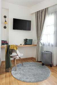 a living room with a television and a suitcase at Petrou Suites in Ioannina