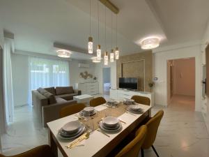 una sala da pranzo e un soggiorno con tavolo e sedie. di Sunshine Homes Luxury Apartmanok a Zamárdi