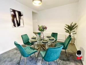 comedor con mesa de cristal y sillas verdes en KozyGuru / 2BR 3Beds / Beautiful Comfortable House / Worsley / Very Convenient Location / Close to local Amenities and Train Station / UMWO018 en Worsley