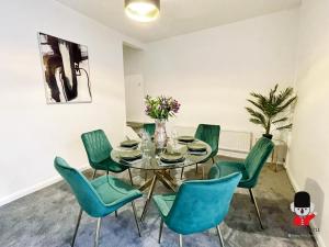 a dining room with a glass table and green chairs at KozyGuru / 2BR 3Beds / Beautiful Comfortable House / Worsley / Very Convenient Location / Close to local Amenities and Train Station / UMWO018 in Worsley