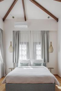 a bedroom with a large bed and two windows at Petrou Suites in Ioannina