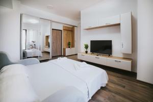 a white bedroom with a large bed and a television at Urban Accommodation - Palas Mall Iasi in Iaşi