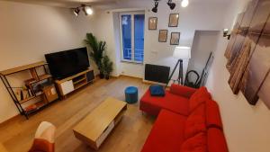 sala de estar con sofá rojo y TV en Appartement neuf et cosy 2 à 6 personnes tout équipé, en Allevard