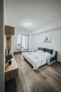 a white bedroom with a large bed and wooden floors at Urban Accommodation - Palas Mall Iasi in Iaşi