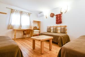 a room with two beds and a table in it at Kfar Hanokdim - Desert Guest Rooms in Arad