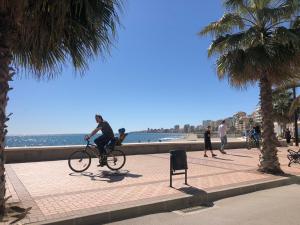 a man riding a bike on a sidewalk near the beach at Charming apartment with a stunning sea view in Málaga