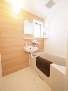 La salle de bains est pourvue d'un lavabo, d'un miroir et d'une baignoire. dans l'établissement La Lumiere Oroku / Vacation STAY 1043, à Naha