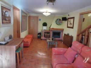 Casa Da Vieira في أورينس: غرفة معيشة مع كنب احمر ومدفأة