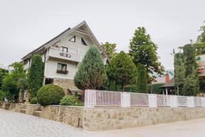 ein weißes Haus hinter einem Steinzaun in der Unterkunft Hotel Velyka Vedmedytsya in Jaremtsche
