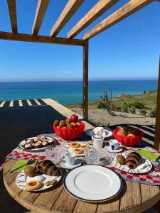 une table avec des assiettes de nourriture sur une table avec l'océan dans l'établissement Tendu' Punta Bianca Glamping Camp, à Palma di Montechiaro