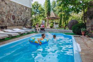 dos niños jugando en una piscina en un patio trasero en Hotel Velyka Vedmedytsya, en Yaremche