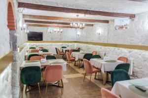 a dining room with tables and chairs and a tv at Hotel Velyka Vedmedytsya in Yaremche