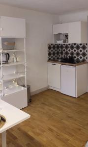 cocina con armarios blancos y suelo de madera en Studio cosy, en Lons-le-Saunier