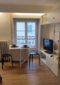 Habitación con escritorio, TV y ventana. en Studio cosy, en Lons-le-Saunier