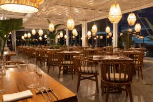 a restaurant with wooden tables and chairs and chandeliers at Plana Resort & SPA in Castel Volturno