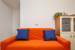 an orange couch with two blue pillows in a room at Casa Salina Bamba in San Teodoro