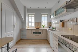 a large kitchen with white cabinets and a tile floor at Villa Walecznych in Zaspa