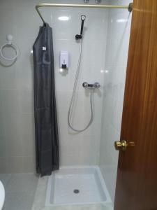 y baño con ducha con cortina negra. en Hostal Conde de Lemos en Ponferrada