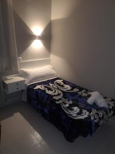 a small bedroom with a bed with a blue and white blanket at Hostal Conde de Lemos in Ponferrada