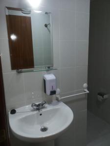 bagno con lavandino bianco e specchio di Hostal Conde de Lemos a Ponferrada