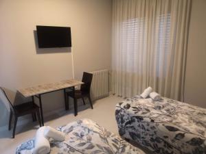 a bedroom with two beds and a desk with a computer at Hostal Conde de Lemos in Ponferrada