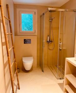 een badkamer met een douche, een toilet en een raam bij Villa mit Meerblick und Pool für 6 Personen in Santanyi