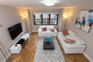 a living room with white furniture and a flat screen tv at Elegant East Side in New York