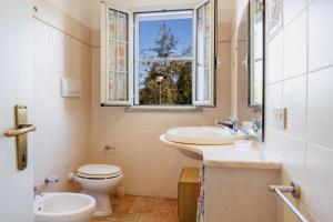 un bagno con un water, un lavandino e una finestra di Casa Attila a Castiglione della Pescaia Altre 19 foto