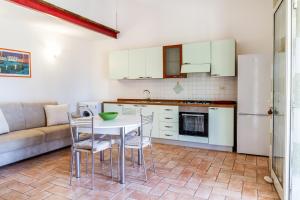 una cucina con tavolo, sedie e un divano di Casa Attila a Castiglione della Pescaia