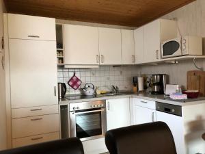 una cucina con armadi bianchi e forno di Ferienwohnung Schwarzwaldglueck a Feldberg