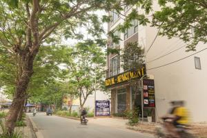 Ein Mann, der eine Straße entlang fährt, neben einem Gebäude in der Unterkunft Royal Hotel & Apartment in Hanoi