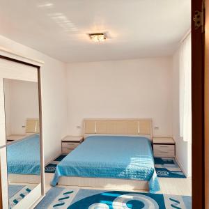 a bedroom with a blue bed and a mirror at Sweet Apartament in Baia Mare