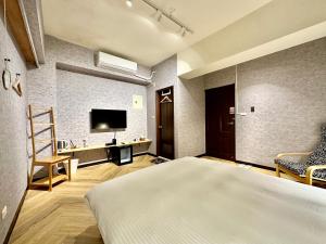 Schlafzimmer mit einem Bett, einem TV und einem Stuhl in der Unterkunft 茗居 House in Taichung