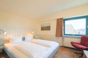a bedroom with a large bed and a red chair at Appartement Greenlön in Westerland (Sylt)