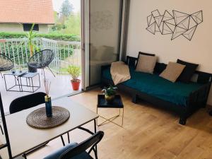 a living room with a green couch and a table at Studio Moderne, Terrasse et Parking in Romans-sur-Isère
