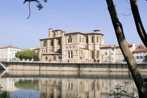 un viejo edificio sentado al lado de un río en Studio Moderne, Terrasse et Parking en Romans-sur-Isère