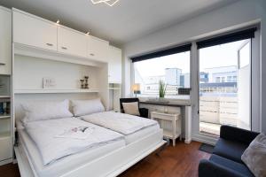 a bedroom with a white bed and a desk and window at Strandgeflüster in Westerland (Sylt)