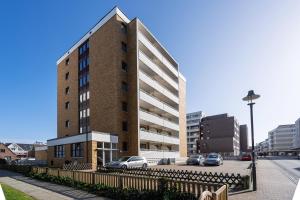 a tall brick building with cars parked in a parking lot at Strandgeflüster in Westerland (Sylt)