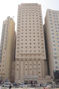 فندق برج الضيافة في مكة المكرمة: مبنى ابيض كبير فيه سيارات تقف امامه