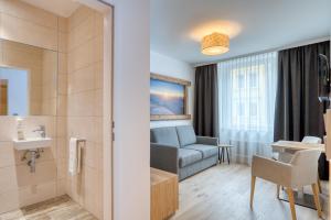 Habitación de hotel con baño y sofá en Leipziger Hof Innsbruck en Innsbruck