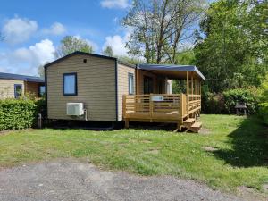 a tiny house with a porch and a deck at Camping la Haie Penée **** in Saint-Quentin-en-Tourmont
