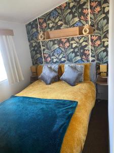 ein Schlafzimmer mit einem großen Bett mit einer blauen Decke in der Unterkunft CT28 Three Bedroom Holiday Home, close to Heated Pool, Amusements and Beach Fantastic Facilities & Top rated holiday park in North Wales PASSES NOT INCLUDED in Rhyl
