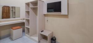a white room with a tv and a stool at RedDoorz near Pantai Pancer Door Pacitan in Pacitan