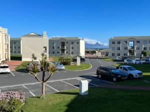 un aparcamiento en un complejo de apartamentos con coches aparcados en Big Bay Beach Front Estate Apartment en Ciudad del Cabo