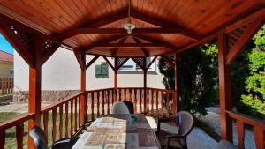 a wooden gazebo with a table and chairs at Villa Napsugár in Balatonlelle