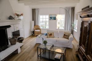 a living room with a white couch and a fireplace at Prachtig gelegen vrijstaand landhuis in Hansweert