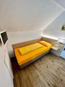 um pequeno quarto com uma cama amarela num quarto em Hotel-Heilsberg em Gottmadingen